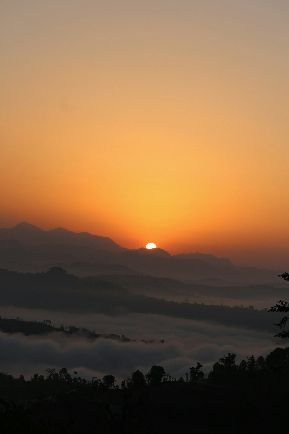 Soleil levant sur des crêtes de montagnes au-dessus d'une vallée remplie de brume